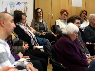 Etwa 7 Personen sitzen und diskutieren.