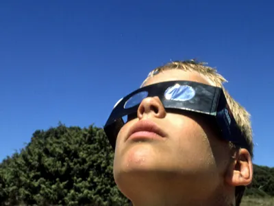 Junge mit Schutzbrille blickt in die Sonne.
