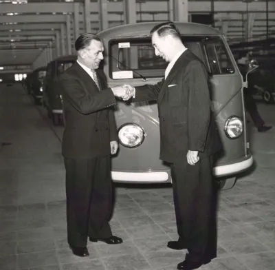 Zwei M&auml;nner sch&uuml;tteln sich die Hand vor einem VW Bulli. Historische Schwarz-Wei&szlig;-Aufnahme.