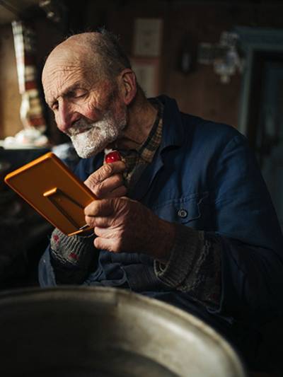 Ein alter Mann rasiert sich mit einem Handspiegel.