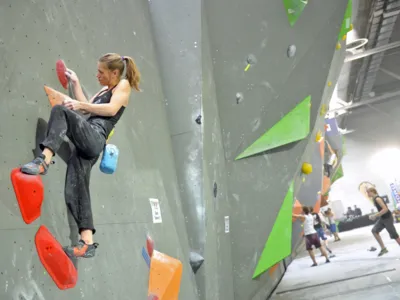 Foto: Eine junge Frau beim Bouldern an der Kletterwand.