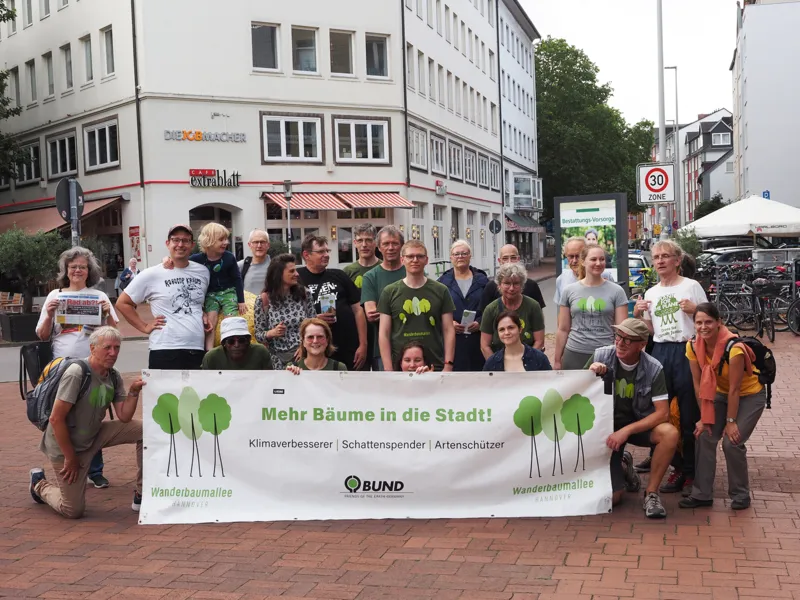 Mehrere Menschen in der Stadt. Sie halten ein Banner auf dem steht "Mehr B&auml;ume in die Stadt!".