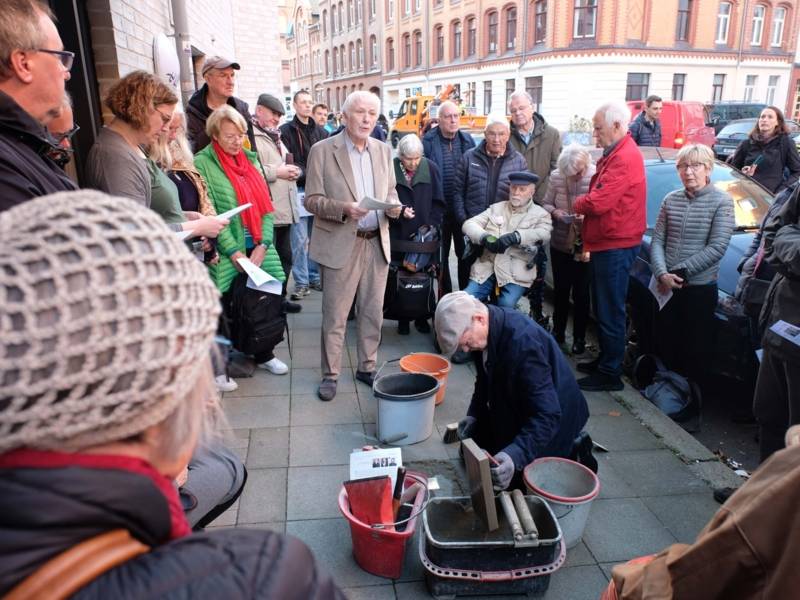 Eine Gruppe Menschen steht um eine kniende Person herum.