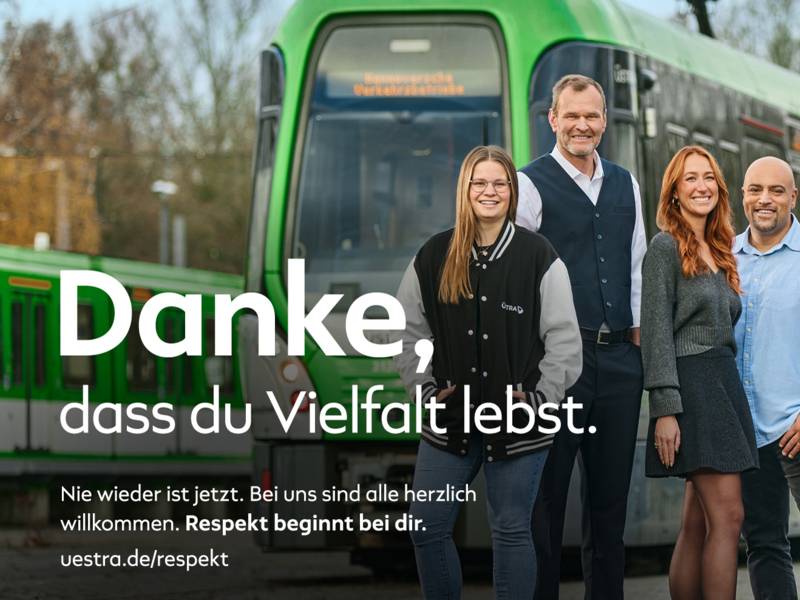 Mitarbeiter der &Uuml;stra stehen vor einer Stadtbahn und daneben der Schriftzug "Danke, dass du Vielfalt lebst"