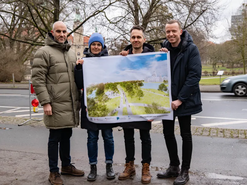 Vier Personen, die eine Visualisierung zeigen. Im Hintergrund ein Park.