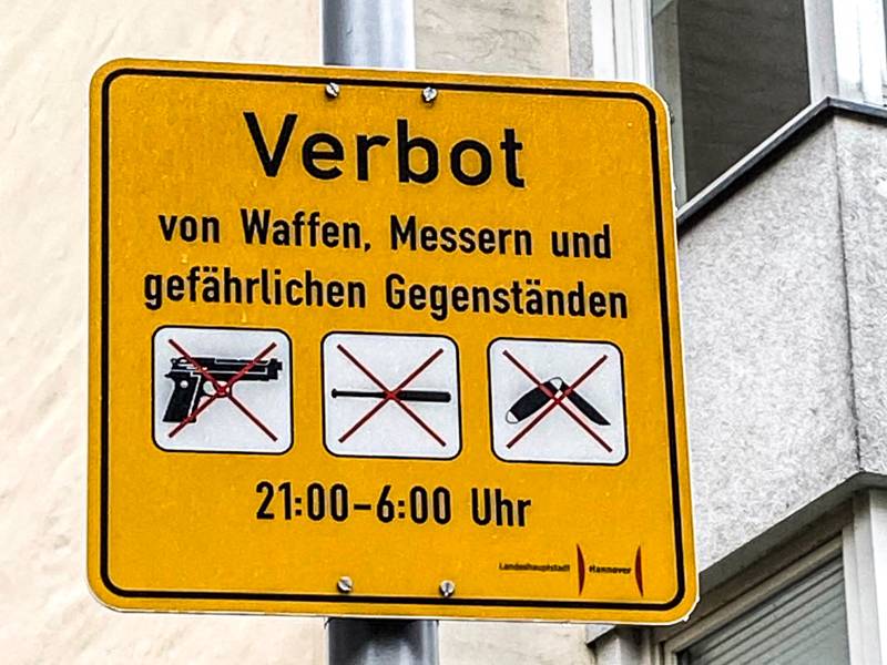 Ein Schild. Darauf steht "Verbot von Waffen, Messern und gefährlichen Gegenständen".