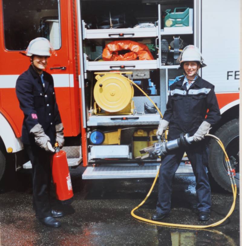 Zwei Feuerwehrleute stehen vor einem TLF.