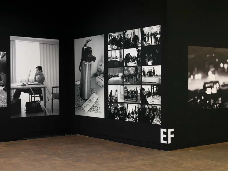 Blick in eine Ausstellung, die gro&szlig;e Fotografien in schwarz-wei&szlig; zeigt. Sie h&auml;ngen an einer schwarzen Wand.