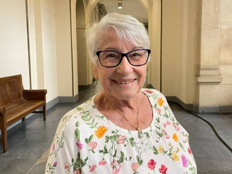 Portr&auml;t einer Frau, die in einem Gang mit schmucken Steinbogen steht.