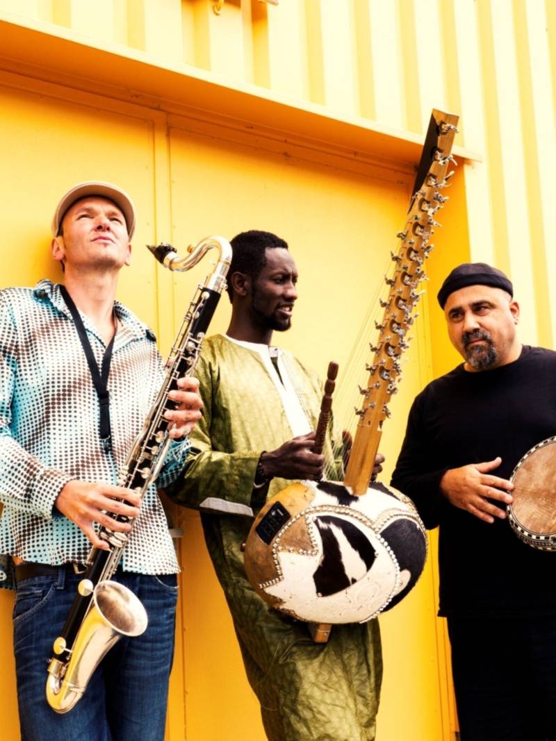 Drei Musiker stehen mit Instrumenten nebeneinander