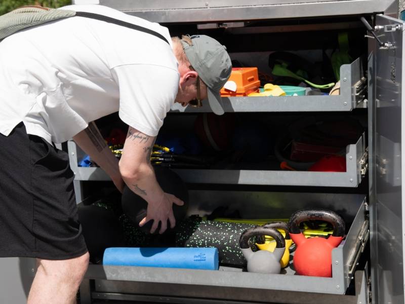 Eine Person, die vor einem Schrank mit Trainingsmaterialien steht.