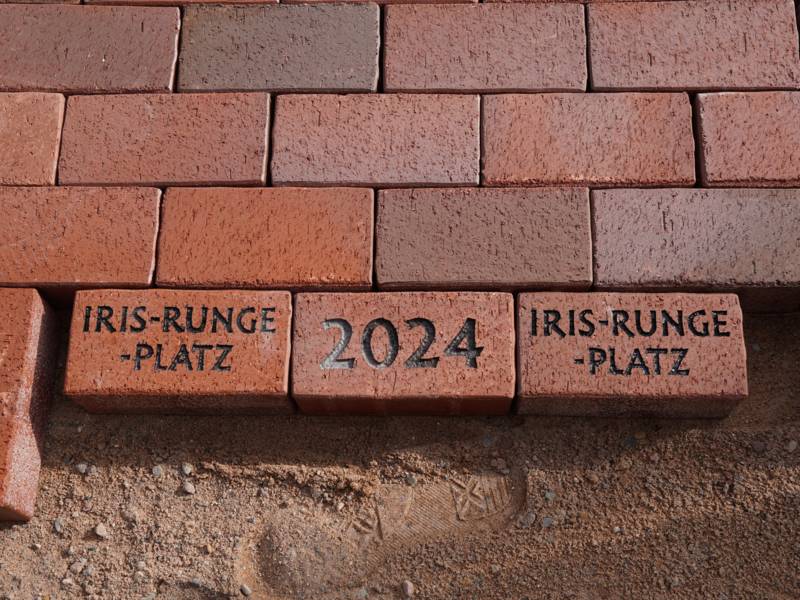 Backsteine mit der Aufschrift Iris-Runge-Platz 2024
