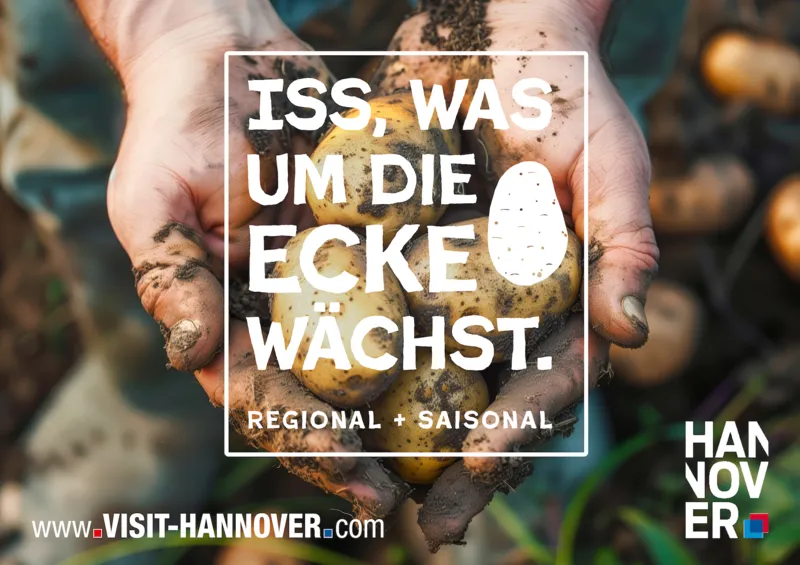 Motiv einer Postkarte. Mittendrin steht "Iss, was um die Ecke w&auml;chst". Im Hintergrund zwei H&auml;nde mit Kartoffeln.