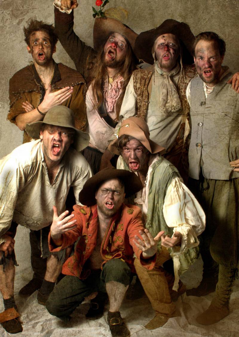 Sieben Männer in Seemans- oder Piratenkostümen gröhlen in die Kamera.