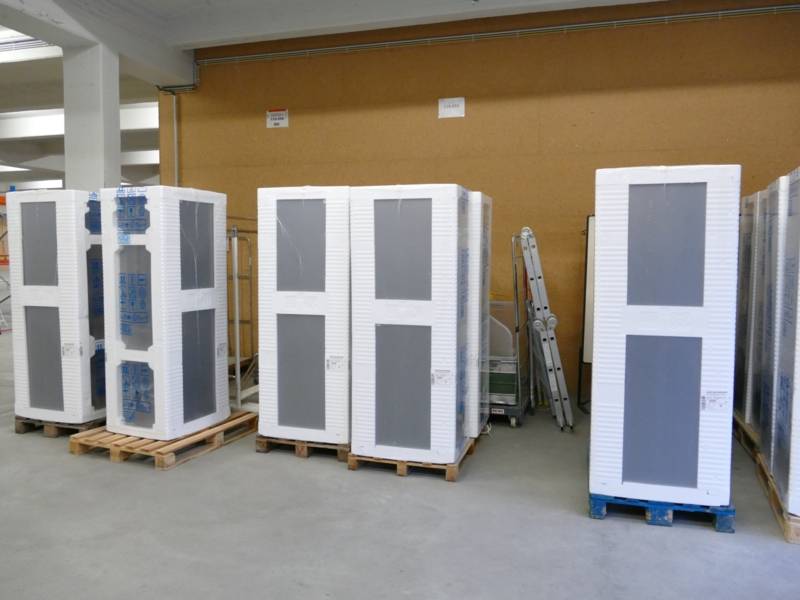 Mehrere wei&szlig;e Verpackungen auf Holzpaletten in einer Halle.