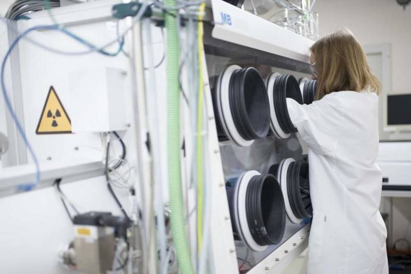 Frau mit Kittel und Schutzbrille an einem gro&szlig;en Laborger&auml;t mit runden &Ouml;ffnungen