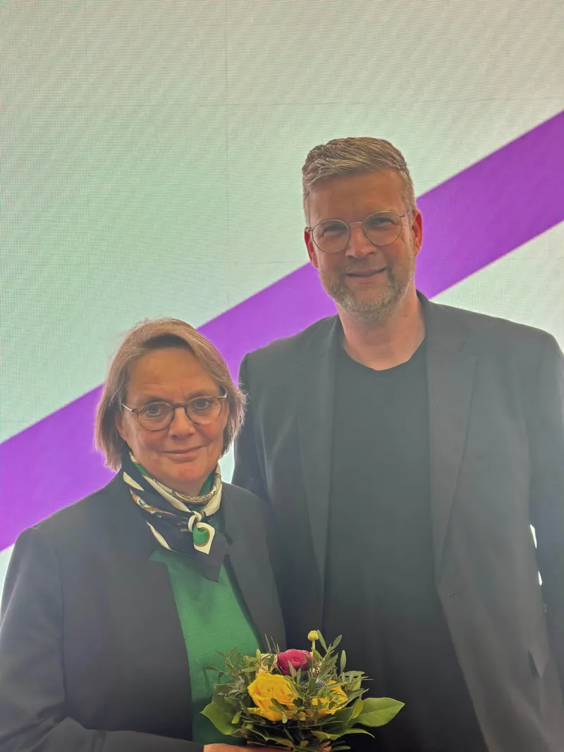Eine Frau und ein Mann stehen vor einer Leuchttafel.