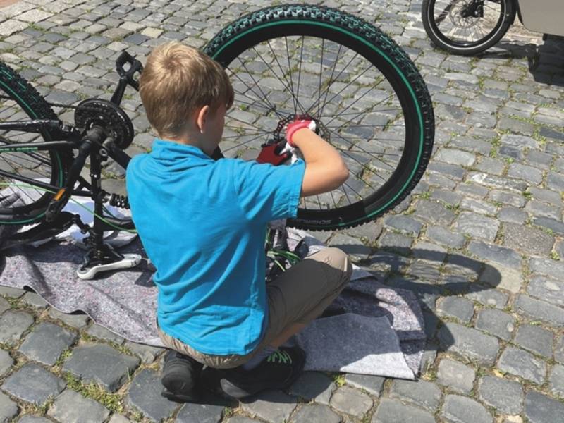 Ein Kind schraubt an seinem Fahrrad.