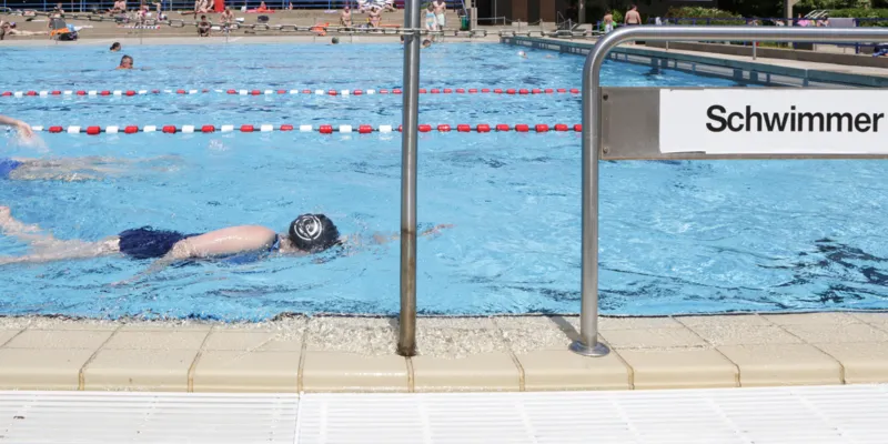 Schwimmerin mit Badekappe im Freibad