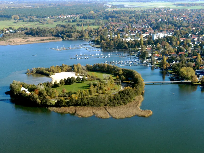 Die Badeinsel im Steinhuder Meer, aufgenommen aus der Luft. Die kleine Insel ist mit Gras und B&auml;umen bewachsen, es gibt eine kleine Bucht ist mit hellem, wei&szlig;en Sandstrand. Ein Steg verbindet die Badeinsel mit dem Festland.