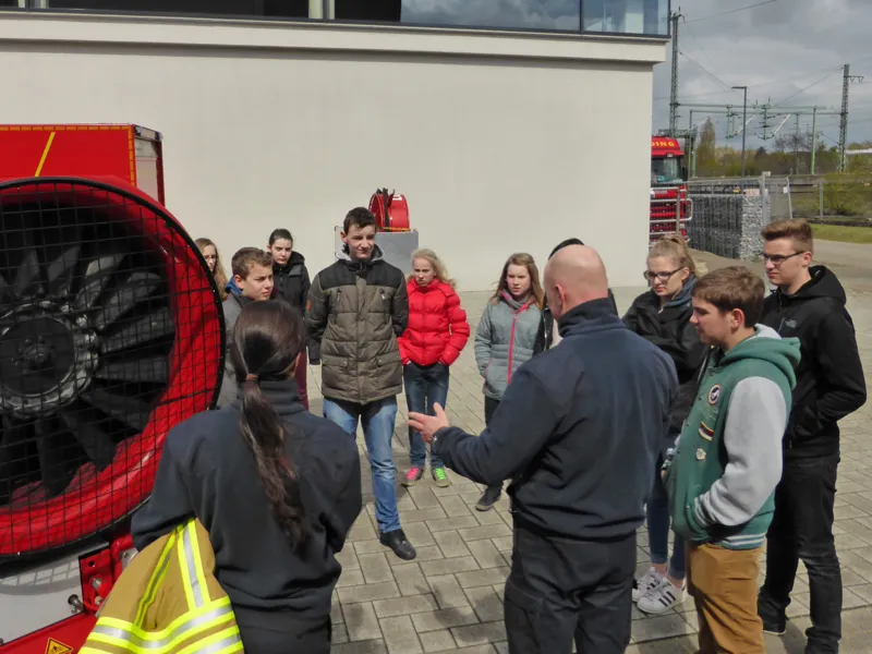 Feuerwehrfrau Marcelina Schneider und ihr Kollege Thomas Petzold erkl&auml;ren den Feuerwehr-Kids die Funktion des L&ouml;schunterst&uuml;tzungsfahrzeuges.