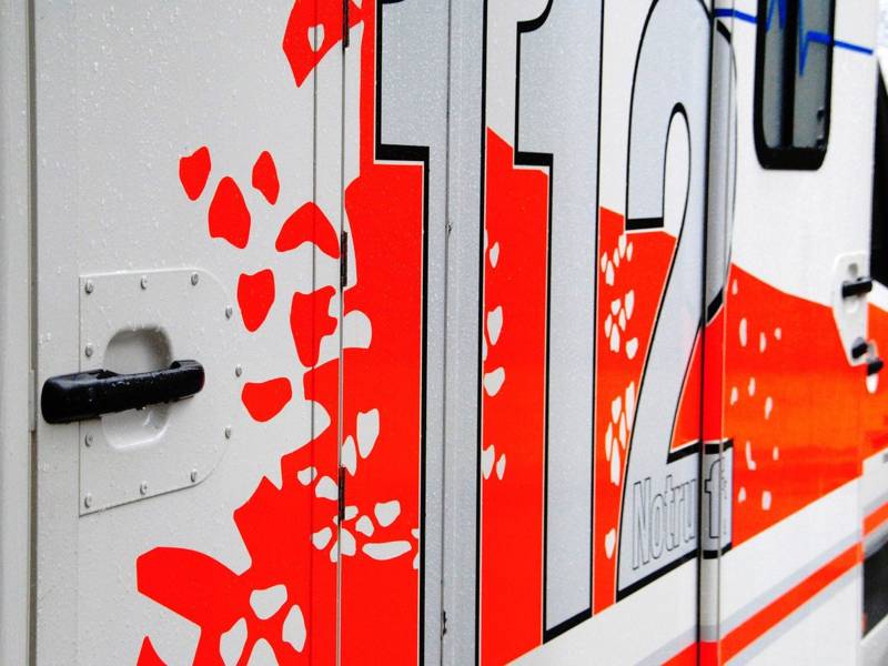 Nahaufnahme der rechten Seite eines weißen Rettungswagen mit roten Flecken und der Aufschrift "112".