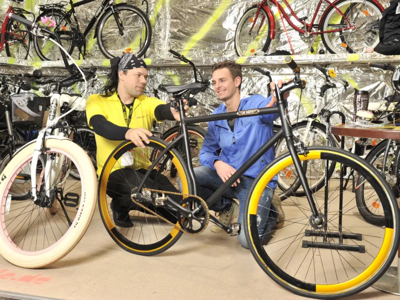 Zwei M&auml;nner begutachten ein Fahrrad.