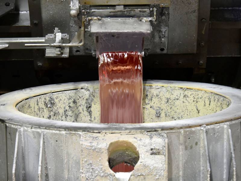 Flüssiges Metall fließt durch einen Augussöffnung aus einem Behälter in eine Auffangvorrichtung.