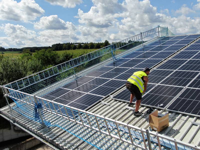 Arbeiter auf einem Dach mit Sonnenkollektoren