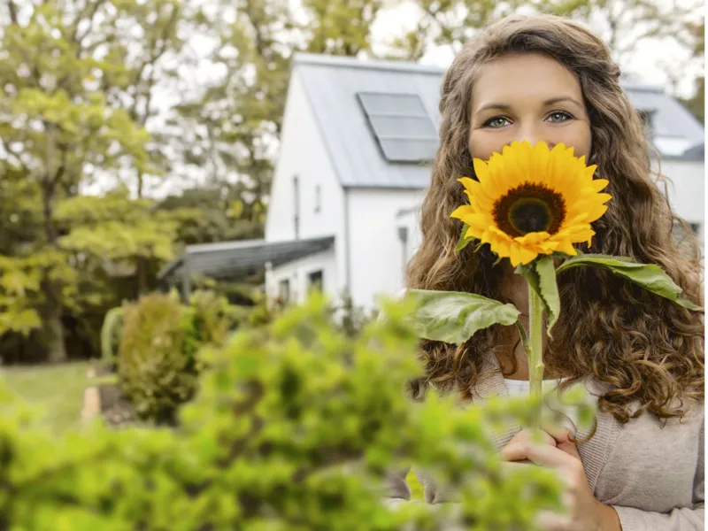 Frau H&auml;lt eine Sonnenblume vor ihr Gesicht