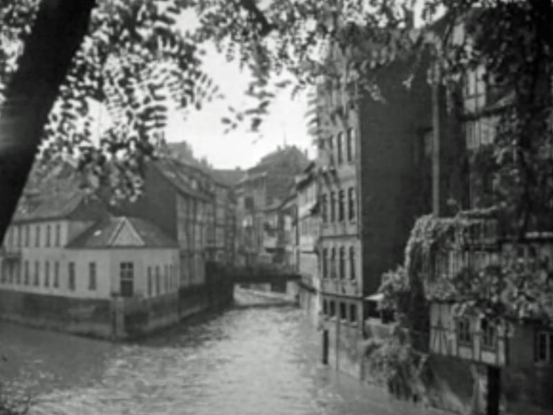 Historisches Foto: Mehrgeschossige Wohnhäuser auf einer Flußinsel und an den Ufern.