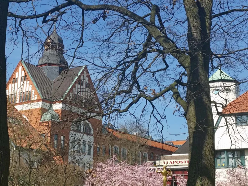 Geb&auml;udekomplex mit bl&uuml;henden B&auml;umen davor.