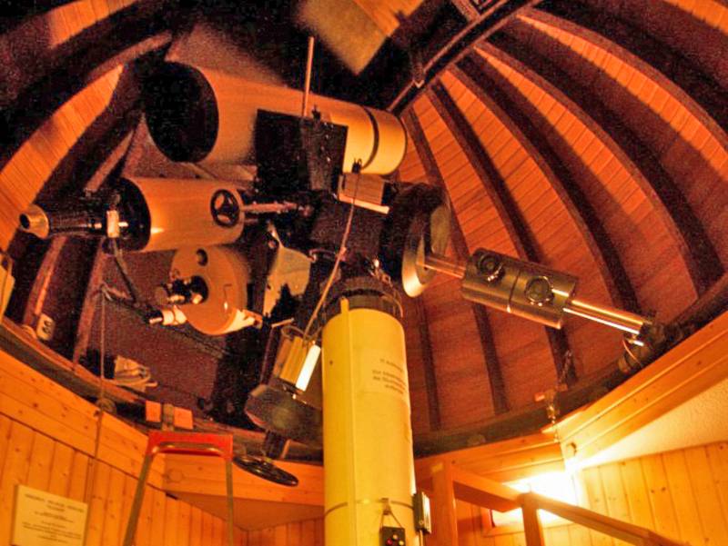 Teleskop unter einer Holzkuppel.