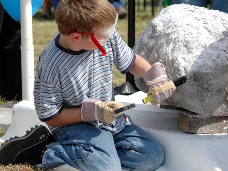 Ein Junge bearbeitet einen Stein.
