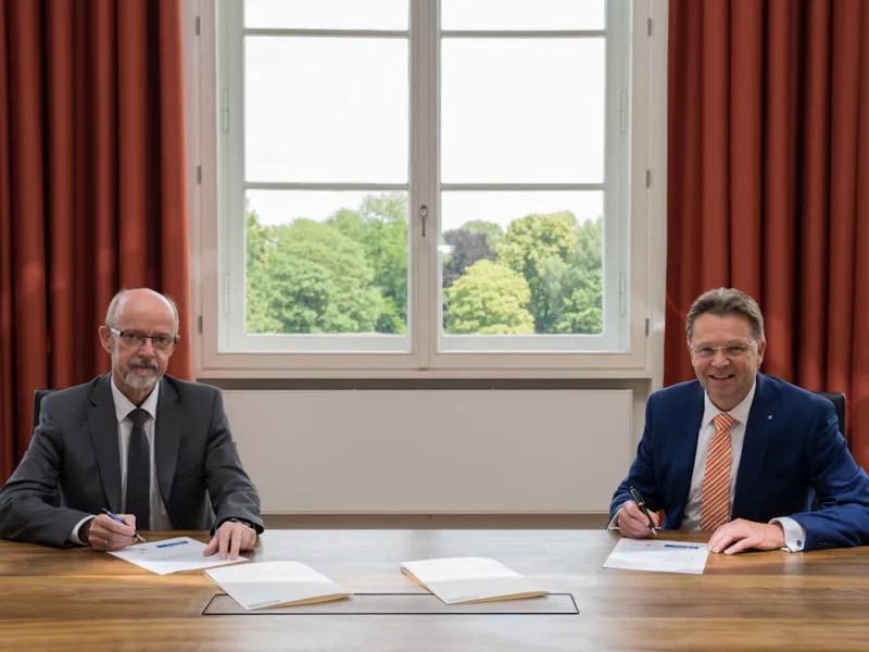 Zwei M&auml;nner sitzen an einem Schreibtisch