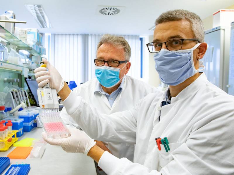 Zwei Männer mit Mund-Nasen-Schutzmasken in einem Labor.