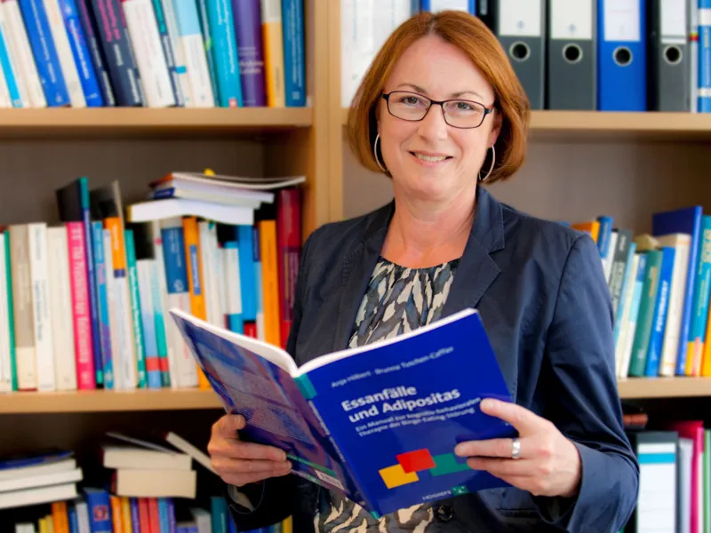 Frau ein ge&ouml;ffnetes Buch in der Hand haltend