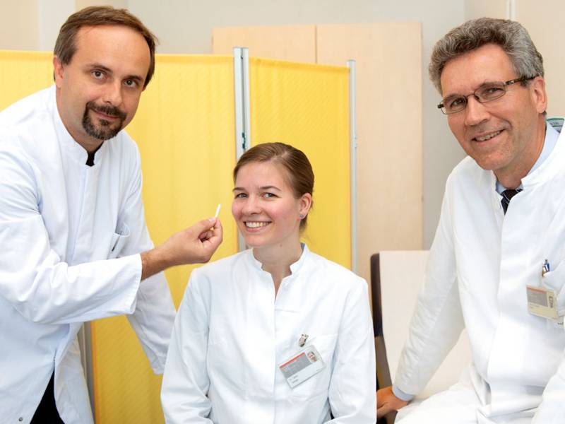 Eine Frau und zwei Männer in weißen Kitteln.