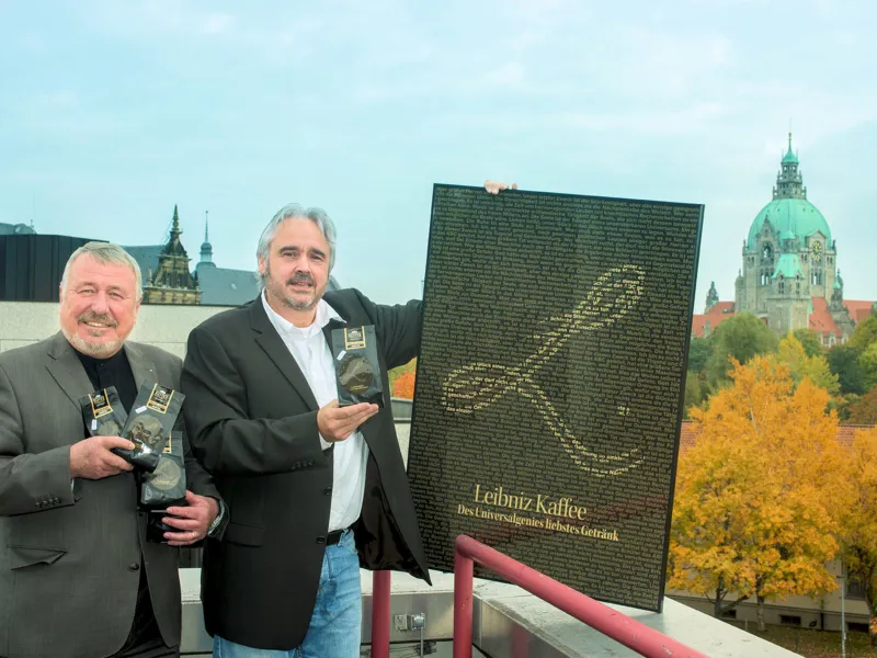 Zwei M&auml;nner halten Kaffee-Packungen in den H&auml;nden, der eine h&auml;lt noch ein Plakat hoch.