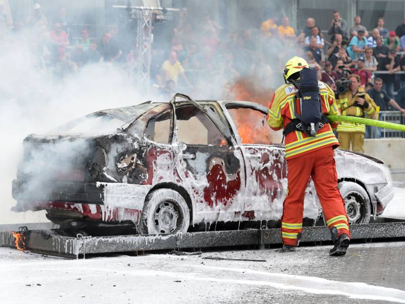 Feuerwehrmann löscht ein brennendes Auto.