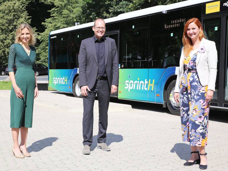 Zwei Frauen und ein Mann stehen vor einem Bus
