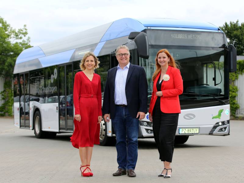 Zwei Frauen und ein Mann vor einem Bus