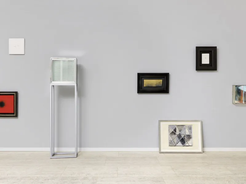 Gerahmte Bilder in verschiedenen Gr&ouml;&szlig;en und unterschiedlichen Aufh&auml;ngeh&ouml;hen an einer Wand.