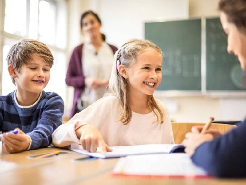 Zwei Kinder und zwei Frauen in einem Klassenzimmer