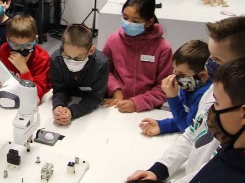 Sechs Kinder an einem Tisch mit einem Roboter