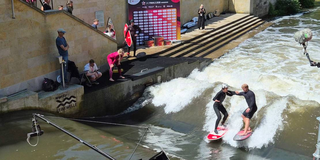 Surfer und Surferin auf der künstlichen Leinewelle