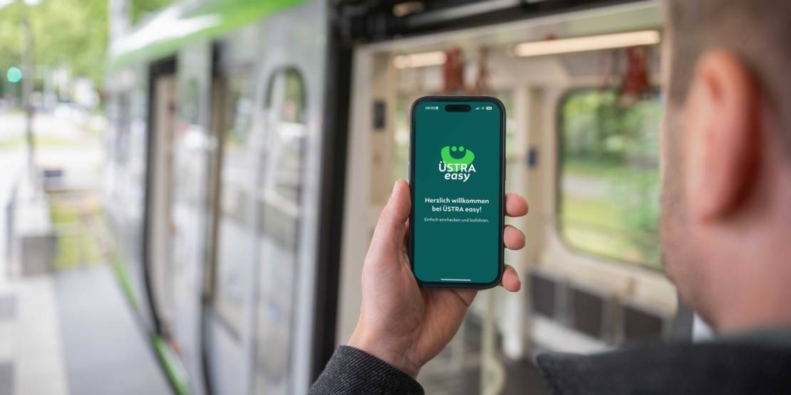 Eine Hand hält ein Smartphone in der Hand und hat die App namens Üstra easy auf dem Display angezeigt
