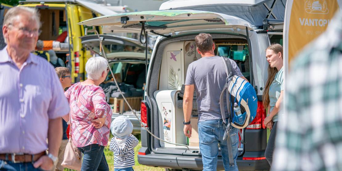 Menschen hinter einem geöffneten Wohnmobil.