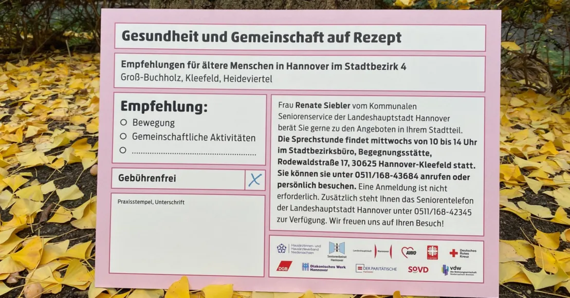 Ein überdimensionales ärztliches Rezept steht an einen Baum gelehnt, drum herum Herbstlaub