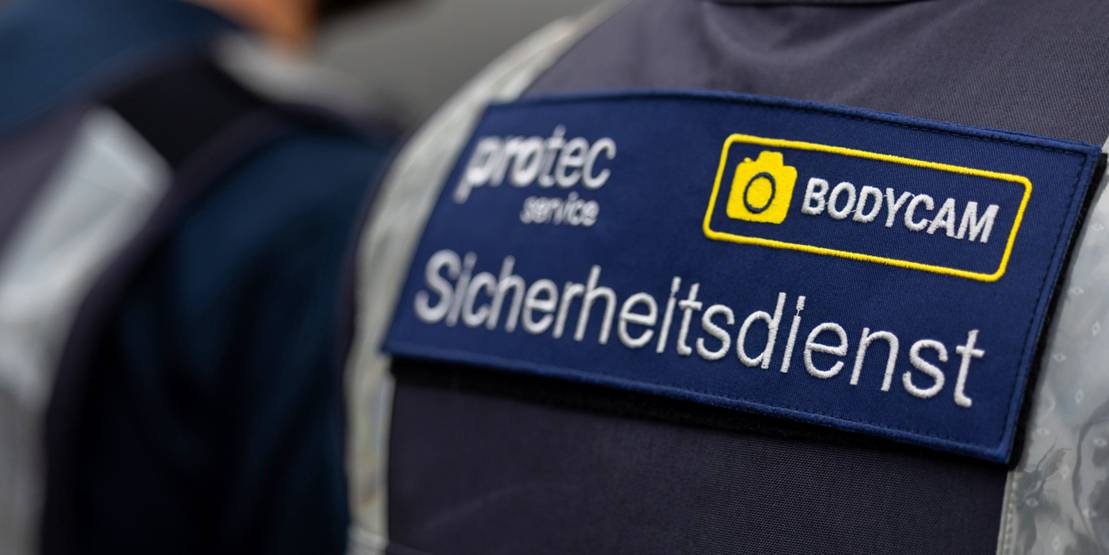 Ein Aufkleber auf der Uniform eines protec-Mitarbeitenden, darauf steht geschrieben: protec, Bodycam, Sicherheitsdienst